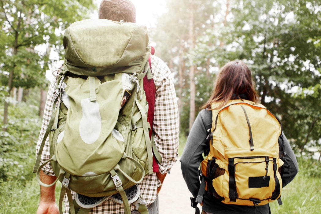 Two hikers walking in the woods with their camping backbacks