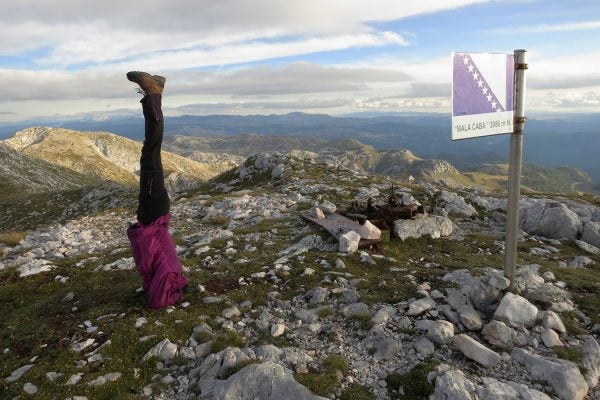 Mountaineer doing a headstand on the summit of Mala Caba