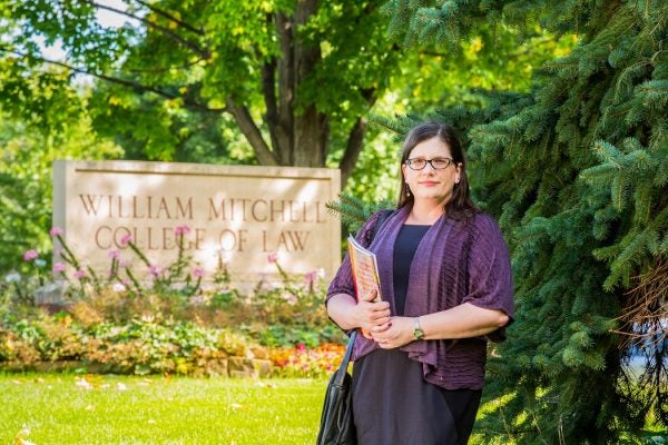 MacArthus Fellow Sarah Deer standing in front of the sign for William Mitchell College of Law