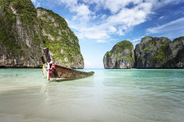 An empty boat at a tropical shore between two rocky masse