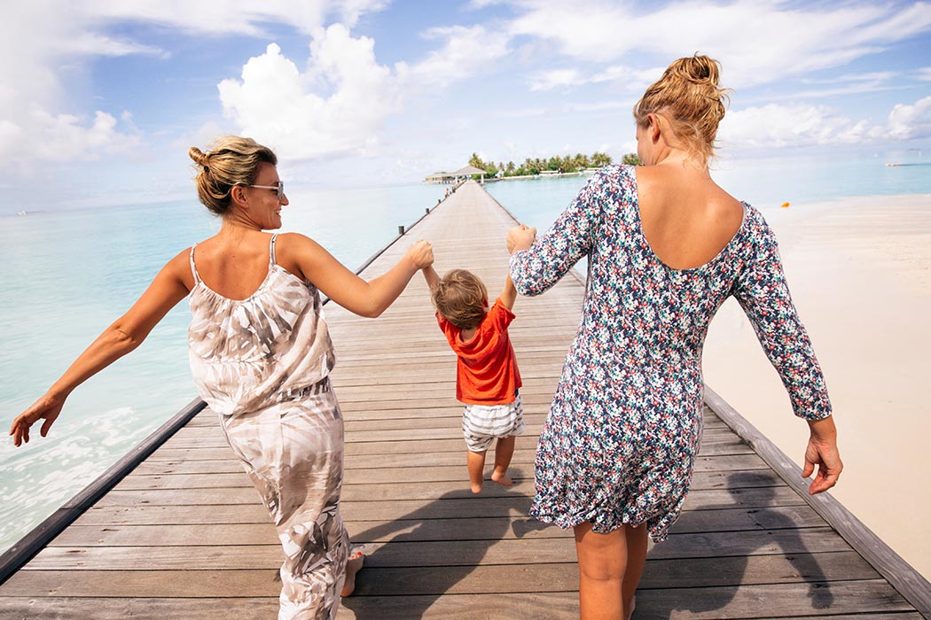 Photo of a young boy spending summer vacation with his two moms on the beach.