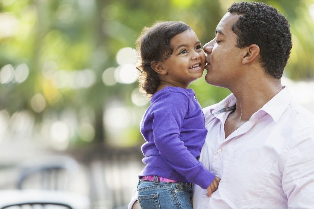 A father kisses his toddler on the cheek