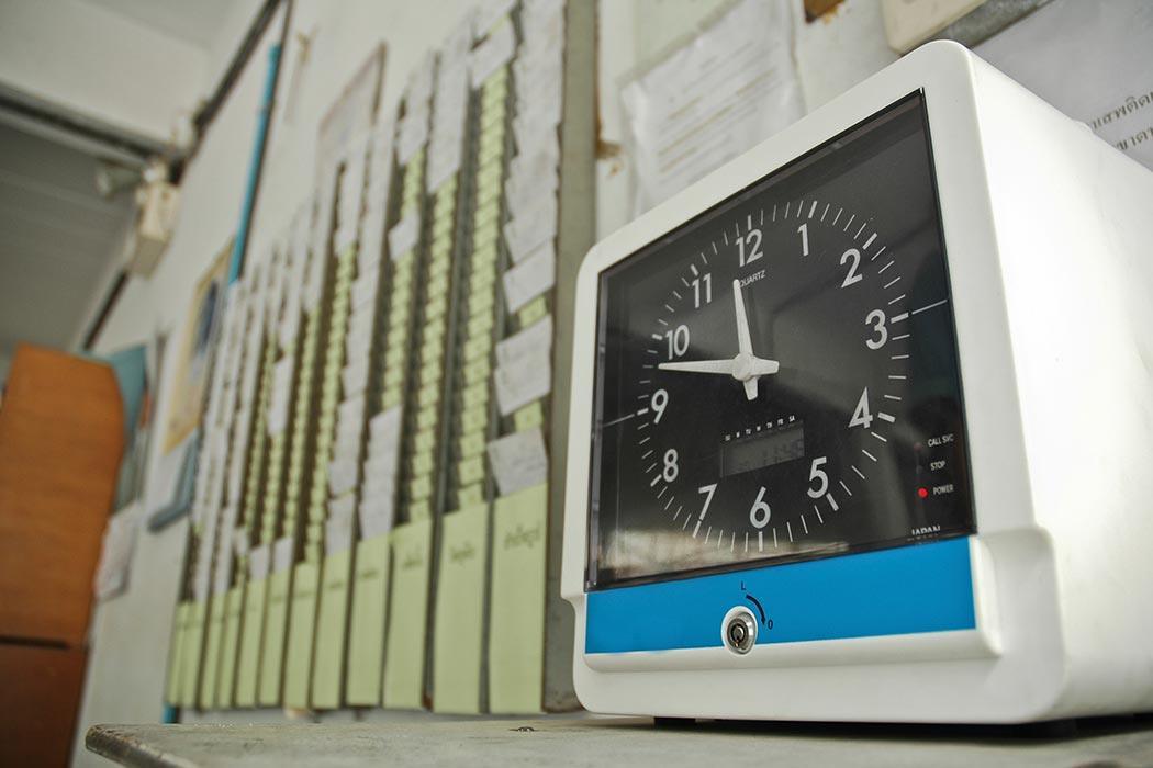 Punch clock next to a wall of timecards