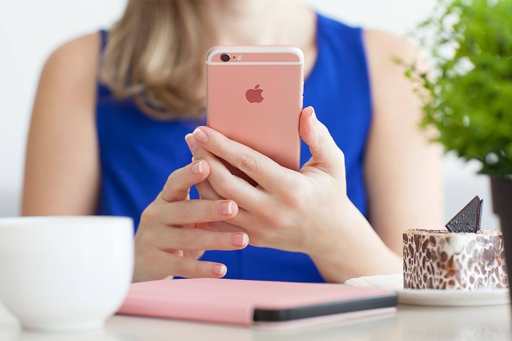 Alushta, Russia - October 25, 2015: Woman holding in the hand iPhone6S Rose Gold in cafe. iPhone 6S Rose Gold was created and developed by the Apple inc.