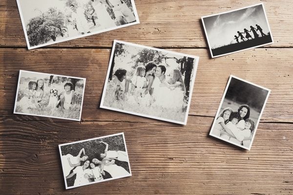 Black and white family photos laid on wooden floor background.