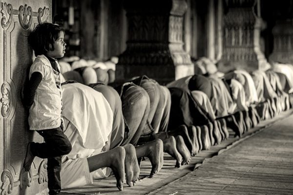 People praying during Ramadan while a while stands close by