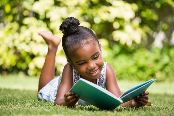 Little girl reading a book at park