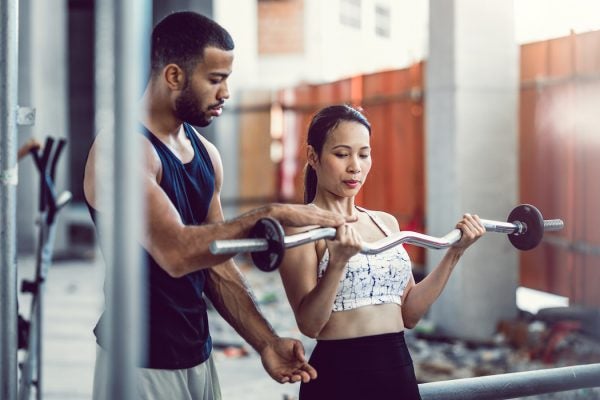 Personal trainer leveling a weight for a lifting client