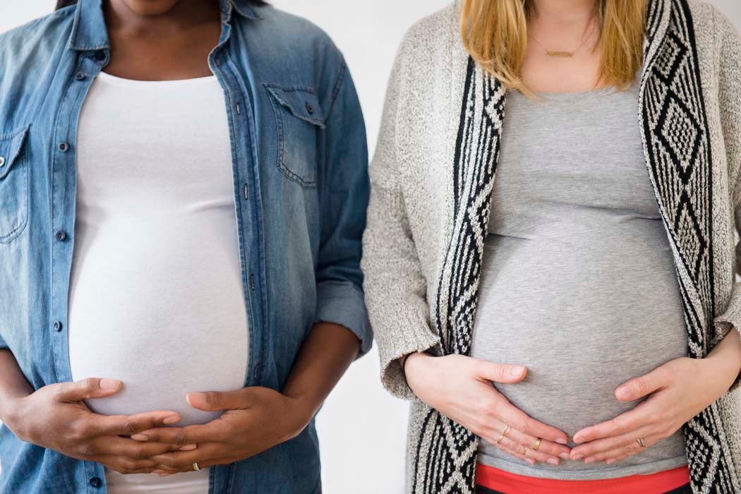 Close up of pregnant women holding stomachs