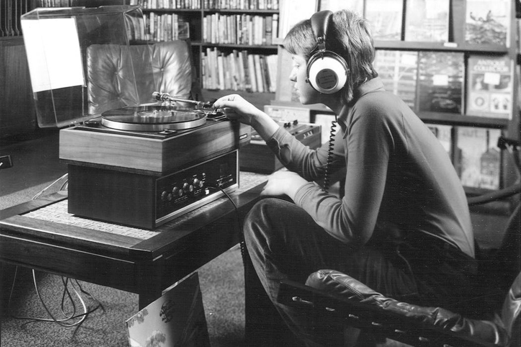 A teenager listening to a record through headphones