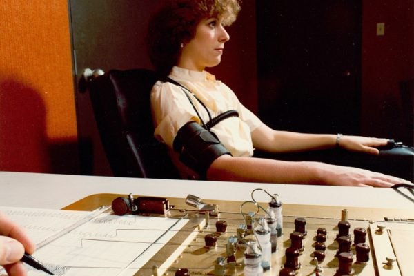 Demonstrating the administration of the polygraph, the polygrapher making notes on the readouts.