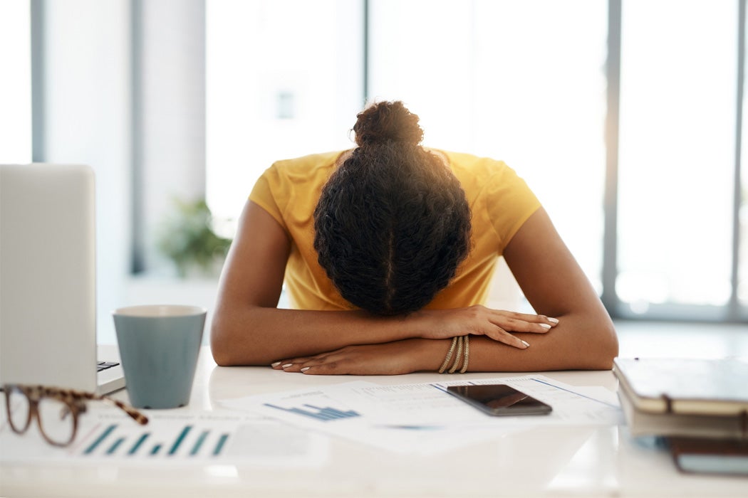 A woman resting her head on her work desk