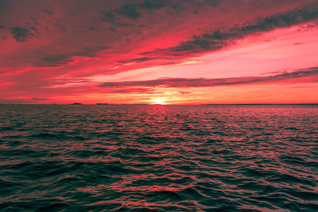 A sunset on the ocean with a red sky