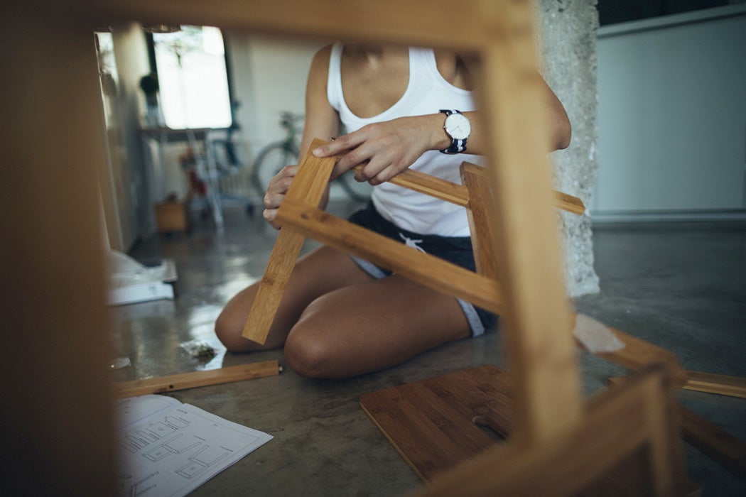 A woman putting a piece of Ikea furniture together