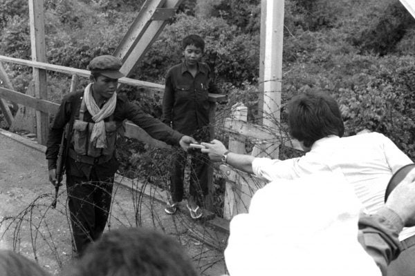 Khmer Rouge guerilla accepts a gift of cigarettes from a waiting French official, May, 1975.