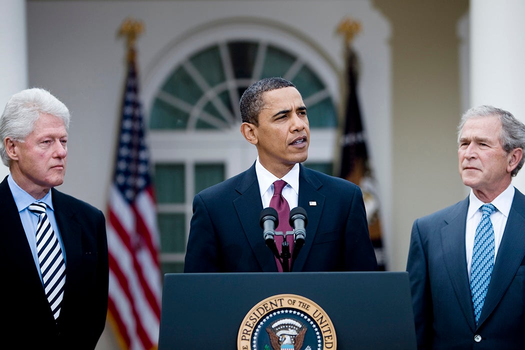 President Barack Obama speaks as former President Bill Clinton (L) and former President George W. Bush (R) listen in the Rose Garden of the White House January 16, 2010. President Obama and the former Presidents Bush and Clinton spoke about the efforts to coordinate American Charitable aid to the earthquake victims in Haiti.