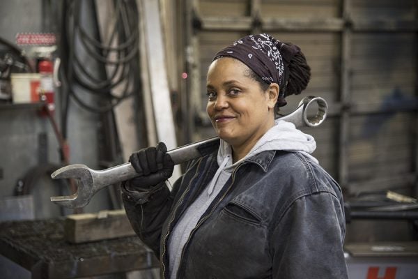 An African American worker carrying a tool in a factory