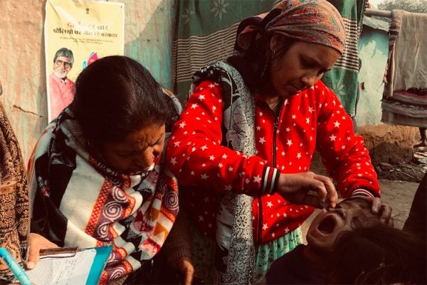 Women administer two drops to a child in India