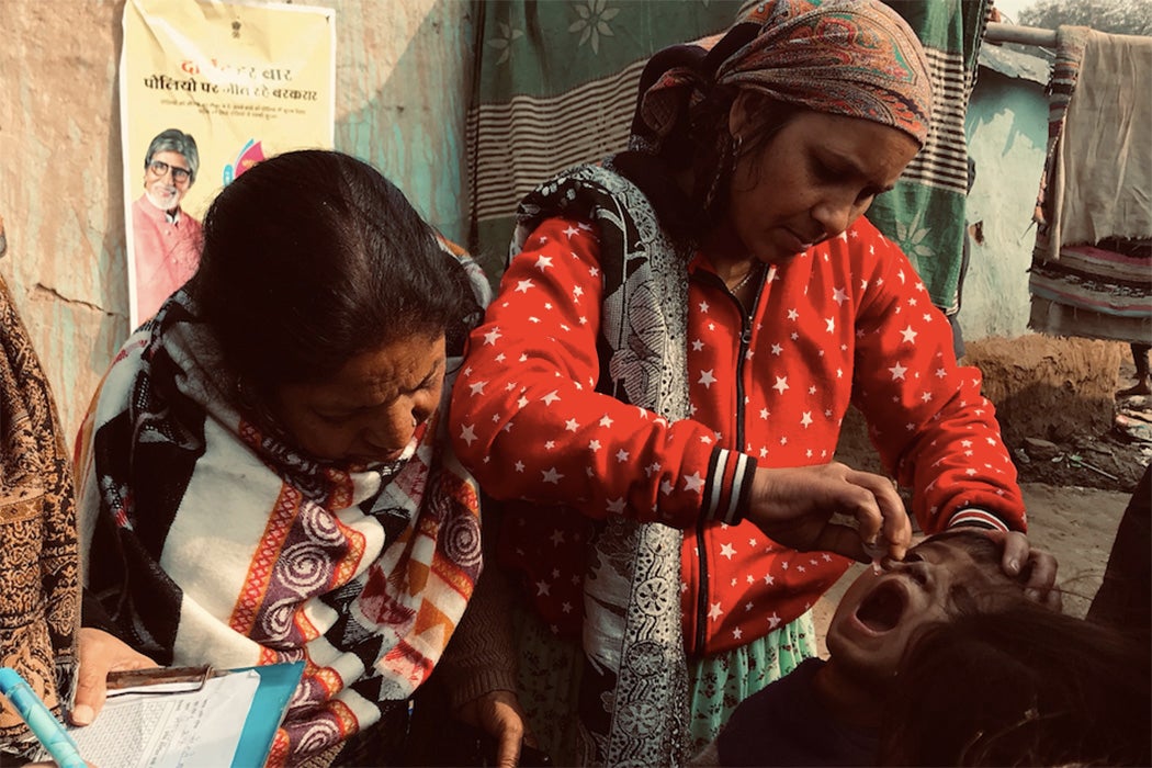 Women administer two drops to a child in India