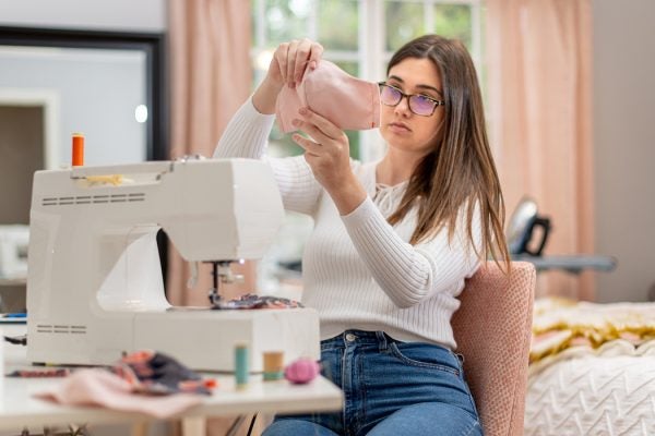 Female Tailor Working From Home Inspects her PPE Mask