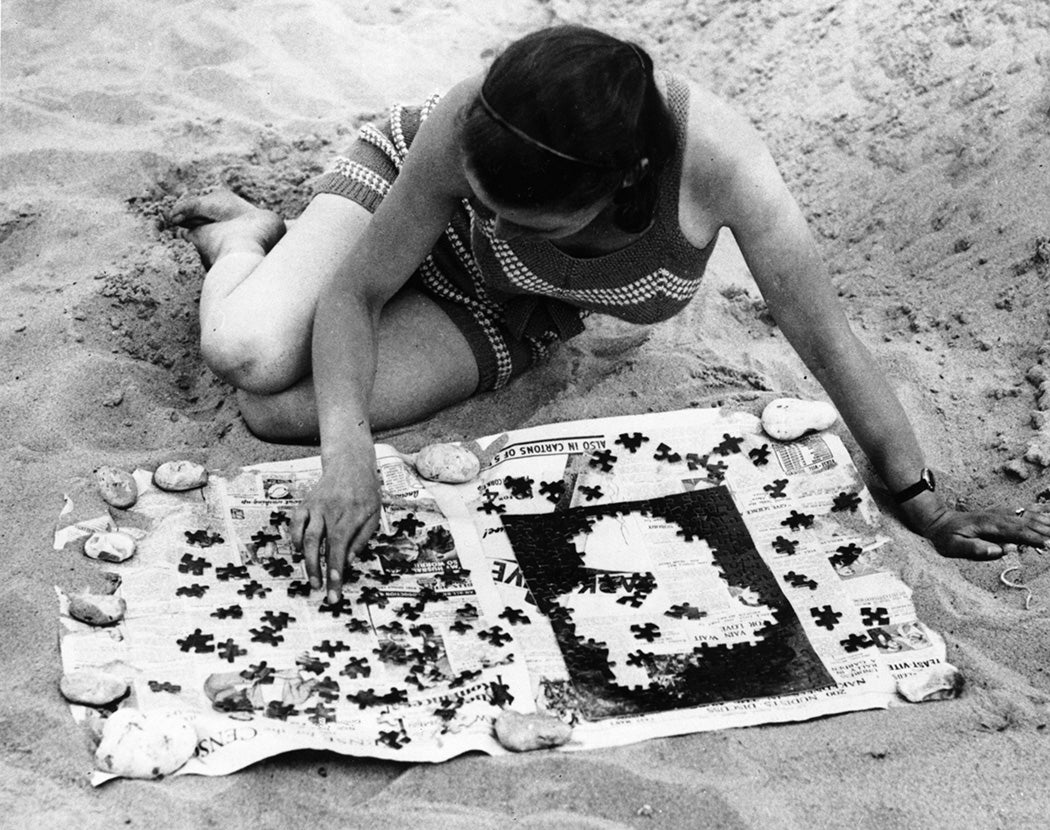 A girl solving a jigsaw puzzle on a beach, 1934