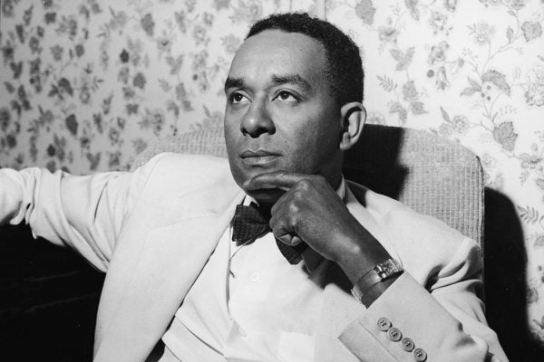 Richard Wright sits in an armchair with his hand to his chin, 1950s.