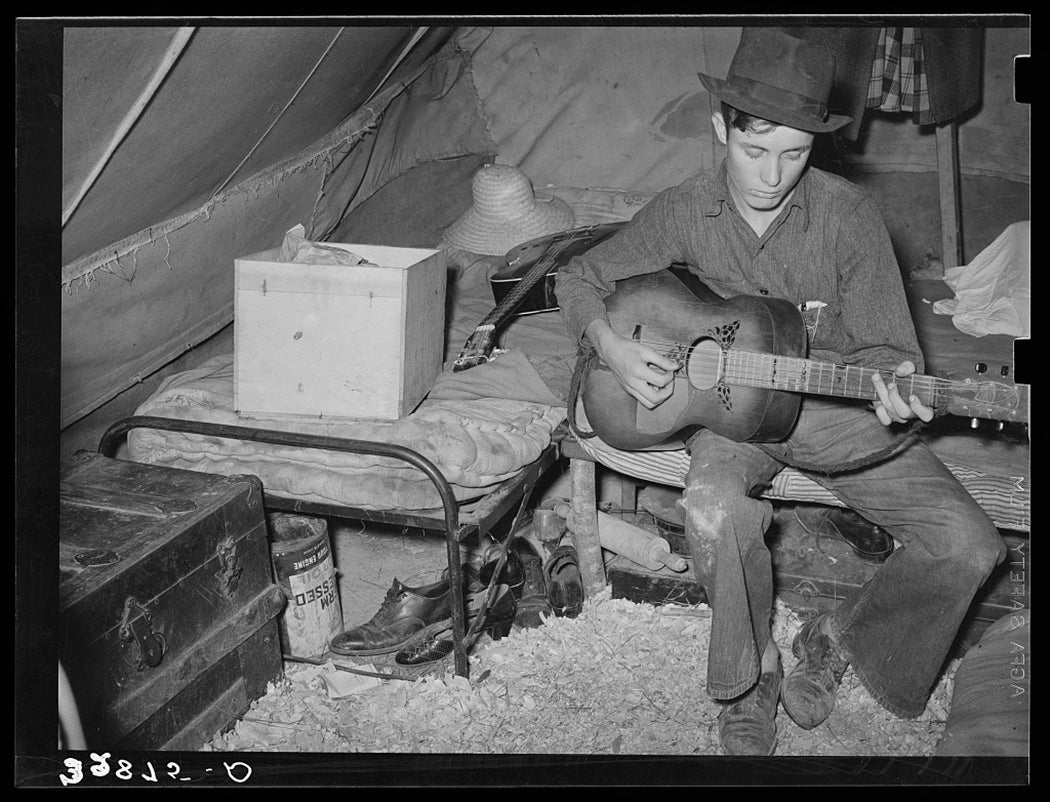 White migrant strawberry picker playing guitar in his tent near Hammond, Louisiana