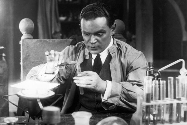 A scientist with staring eyes pours liquid from one test tube to another in