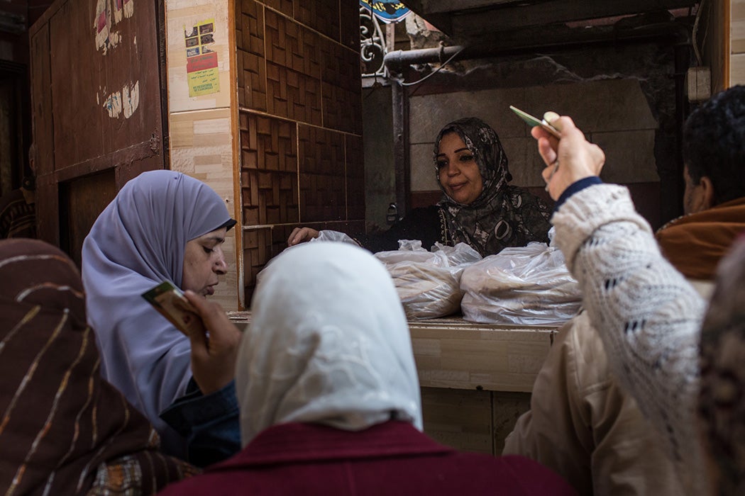 Customers hold out subsidy cards as they buy fresh bread on December 15, 2016 in Cairo, Egypt.