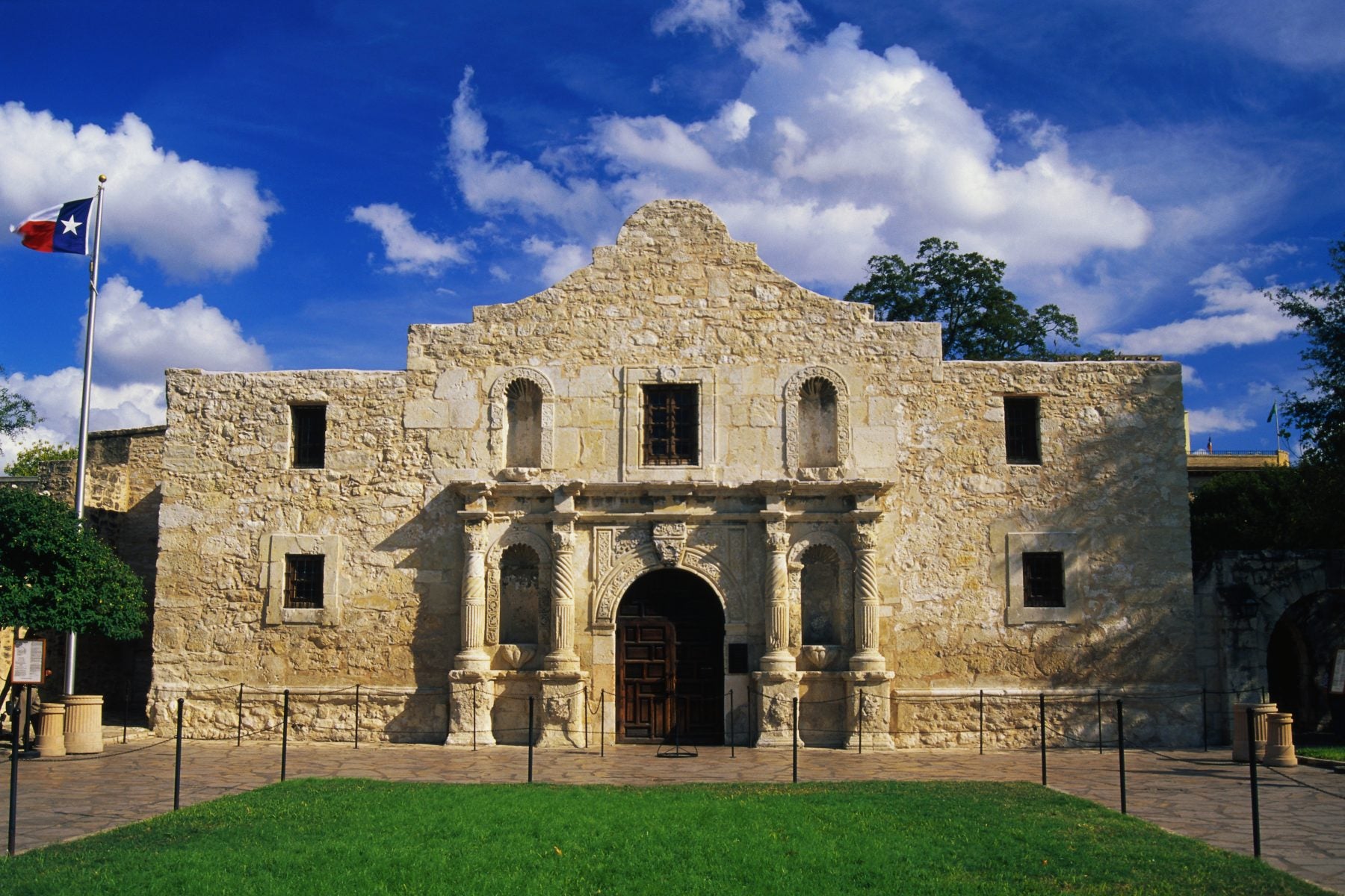 The Alamo by day with the Texas flag waving