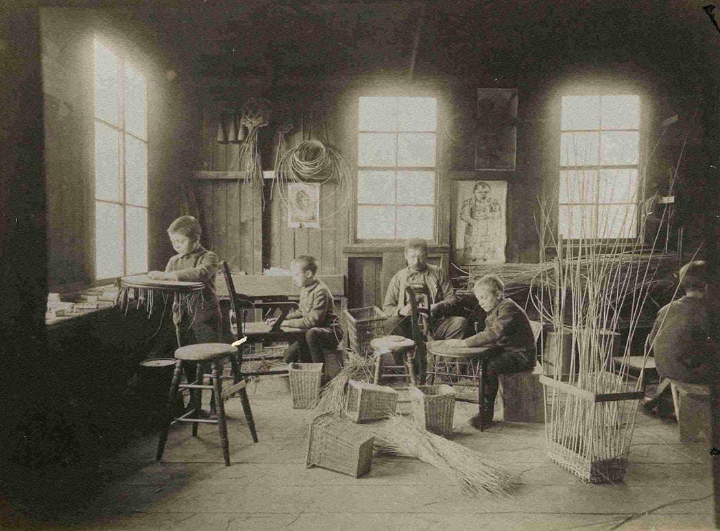 Interior scene from the Orphan Asylum of the City of Brooklyn, NY. Teacher and boys caning chairs in the orphanage workshop. 1890