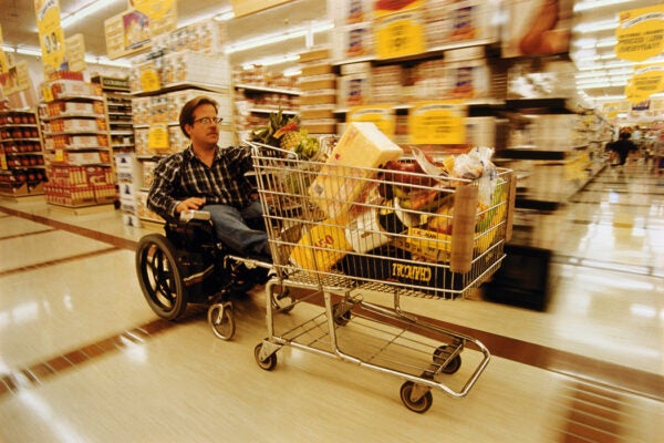 A man in a wheelchair pushing a shopping cart