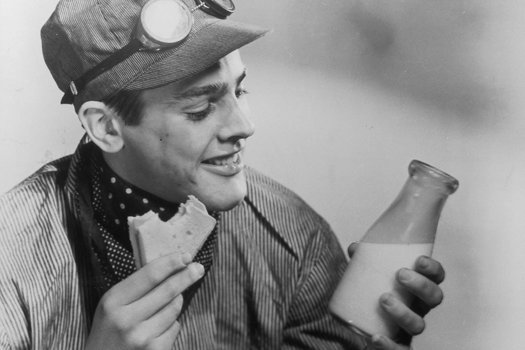 A railroad worker enjoys a sandwich and bottle of milk during his lunch break, circa 1950