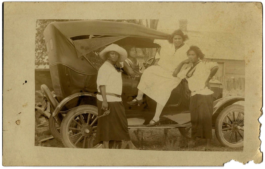 Postcard Photograph of an Unidentified Group of Four Women Posing on a Car